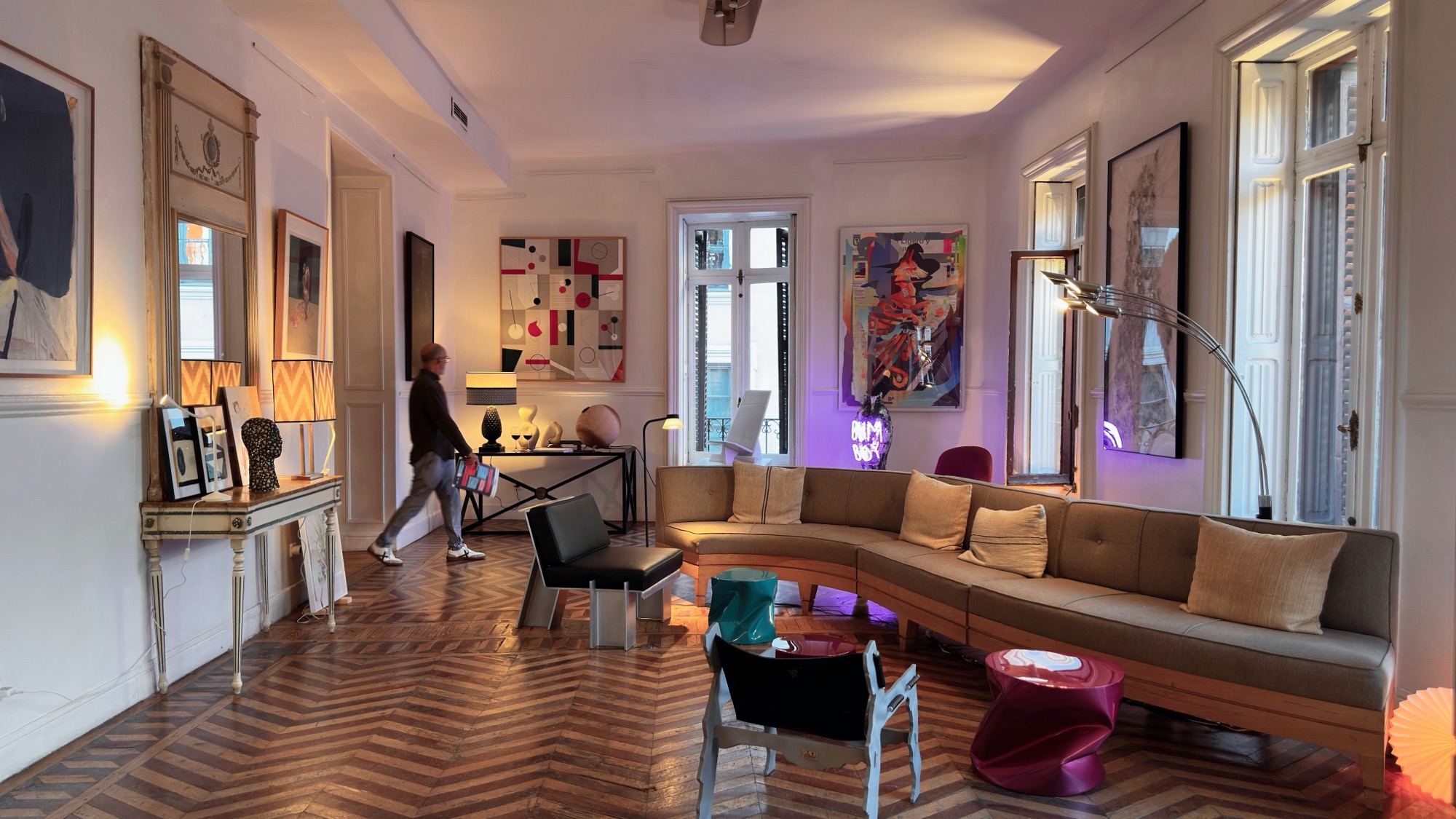 Salón con sofá curvo, obras sobre papel y mesas lacadas