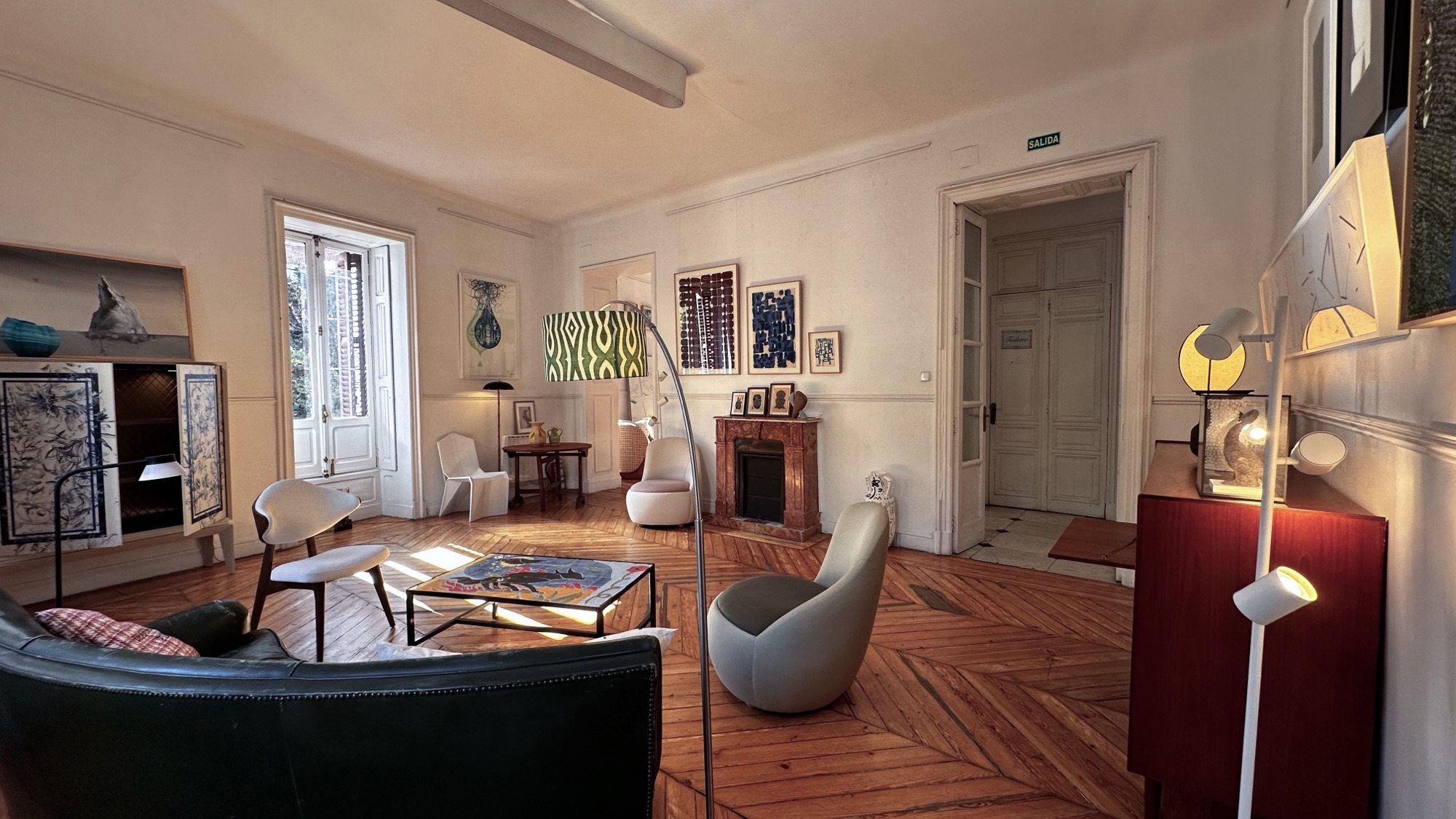 Salón con chimenea, obras enmarcadas y butacas de diseño